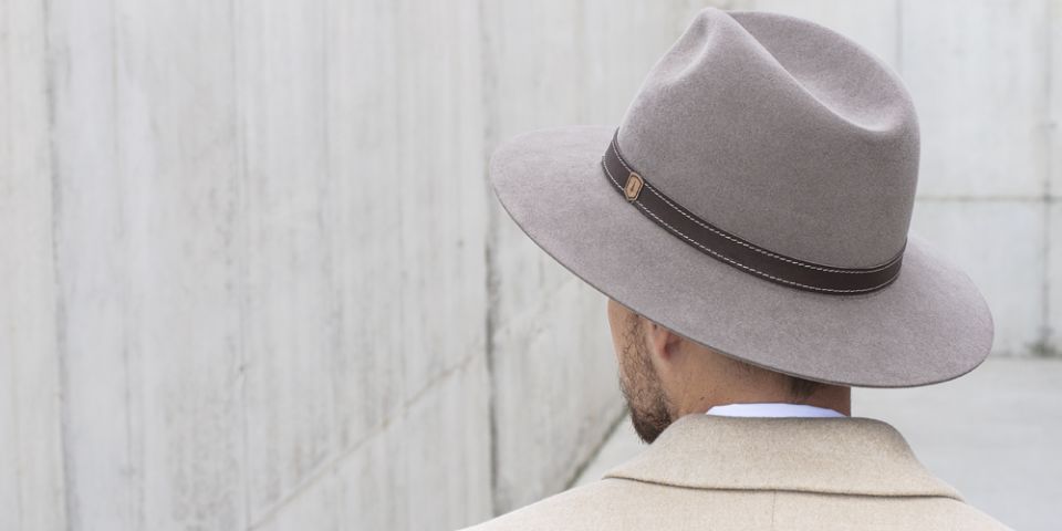 A man wearing brown hat with wooden detail and brown coat. A man wearing brown hat with wooden detail and brown coat.